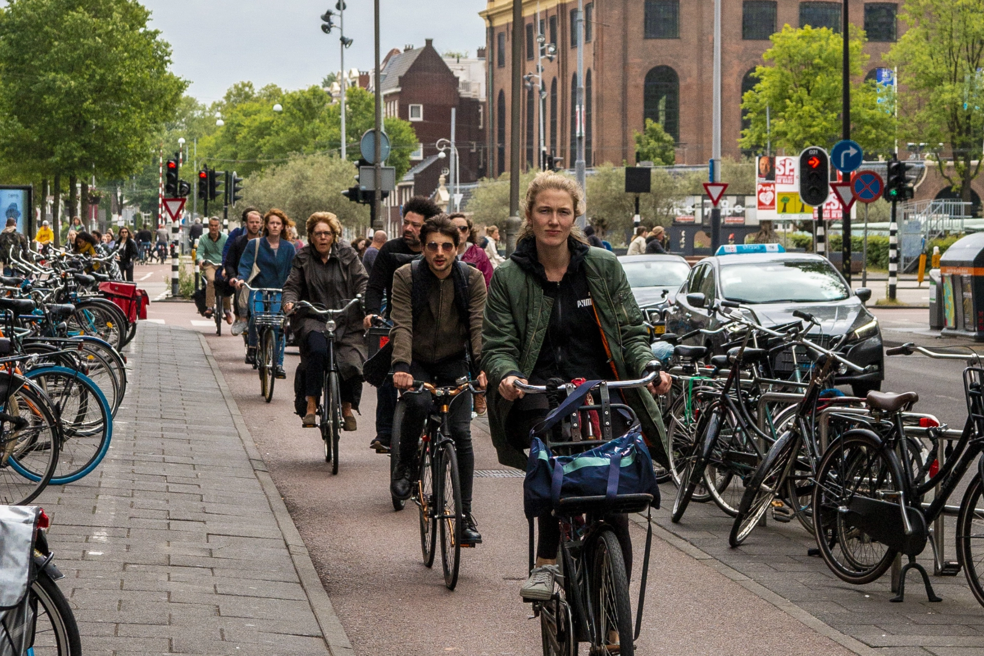 illustration of the article: several people of all ages ride bicycles in a city one behind the other